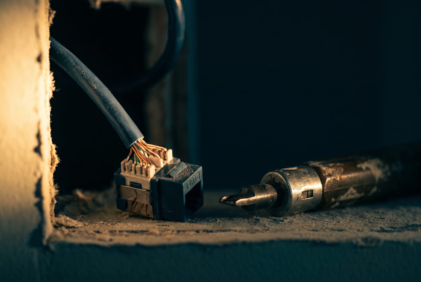Extreme close-up of a punched-down keystone jack and a labeled cable pair in a wall box, copper conductors seated and combed