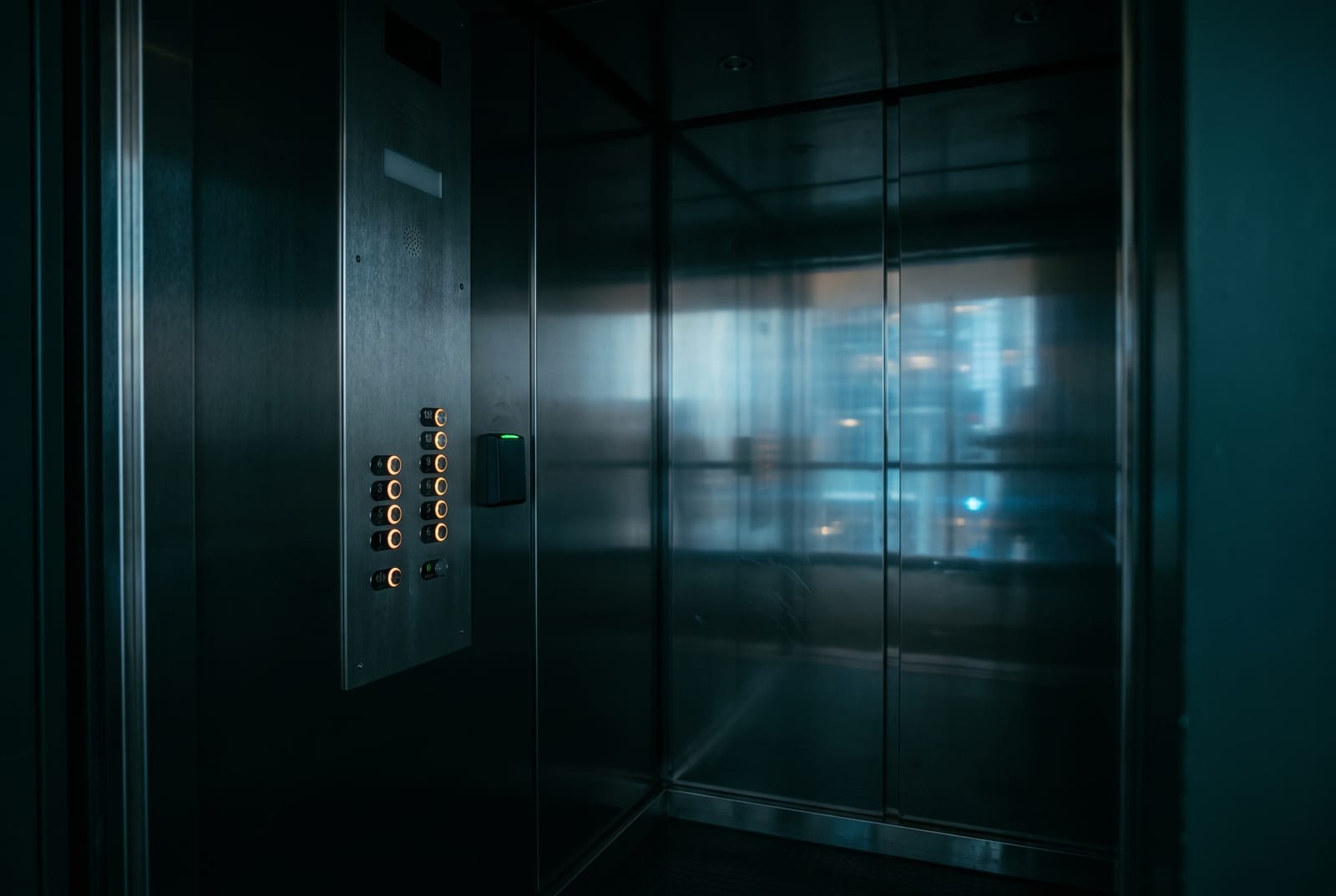A card reader mounted in the car operating panel of an elevator cab, beside the floor buttons